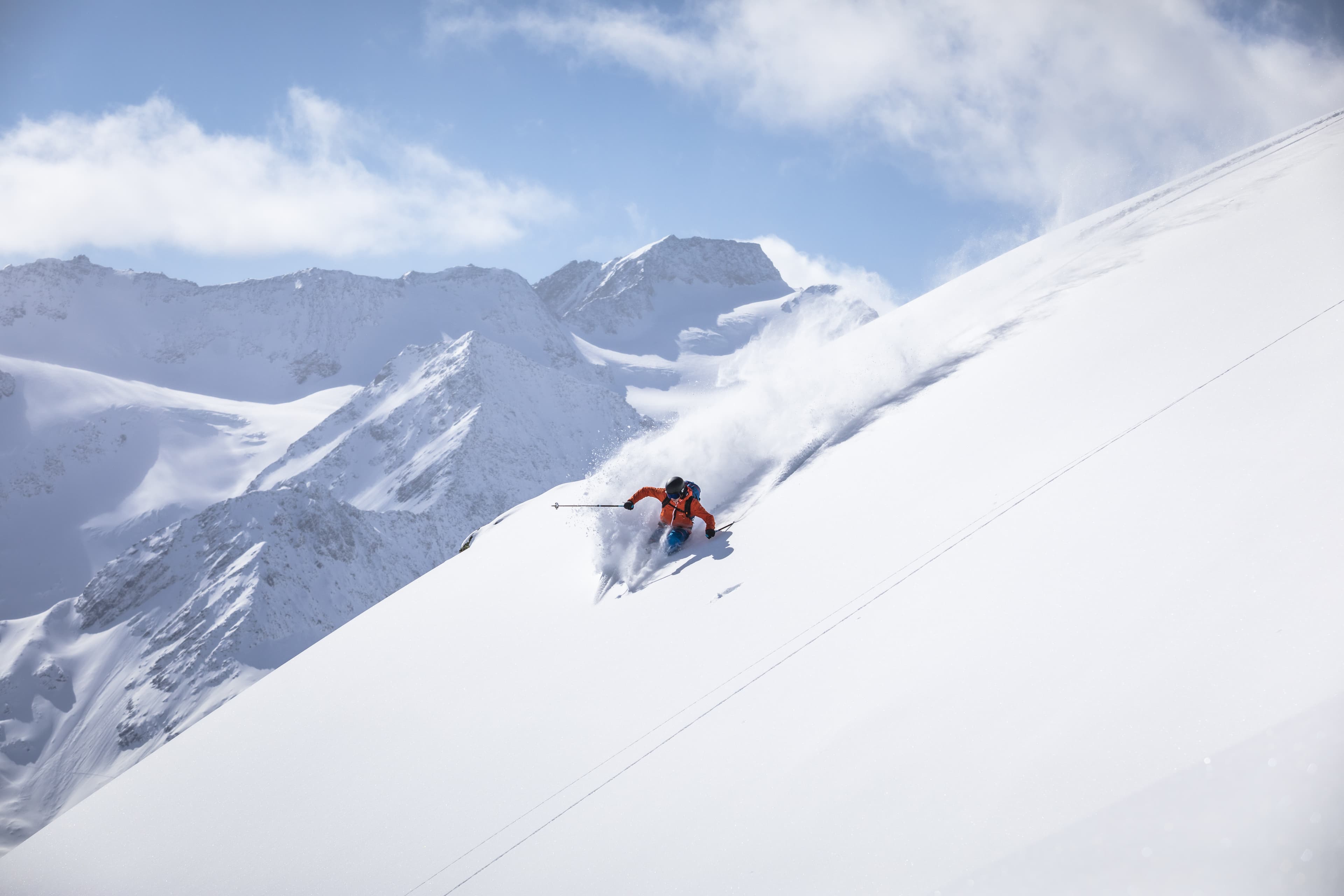 Skiier in red jacket turning on off piste slope atop a mountain